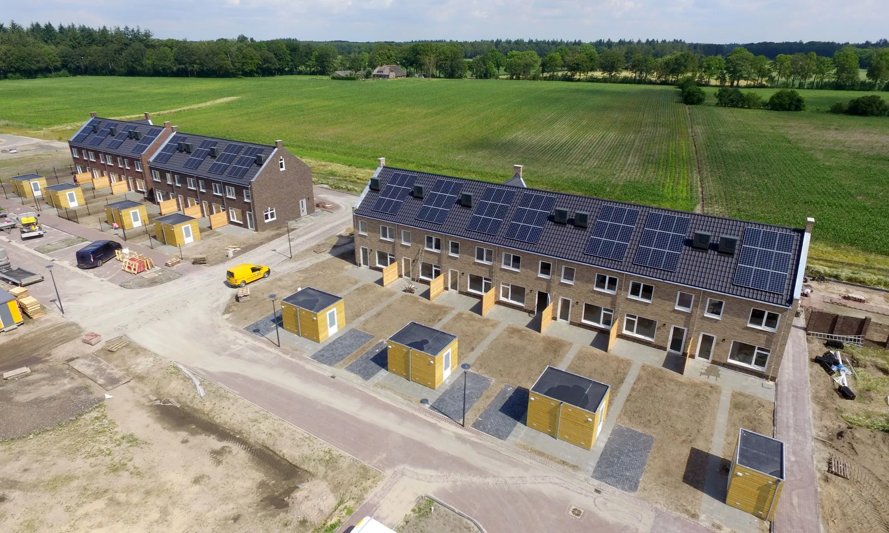 Nieuwbouwwijk met strakke, witte rijtjeshuizen met zwarte daken met zonnepanelen.