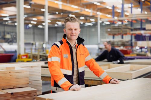 Man poseert in de fabriekshal in een oranje jas