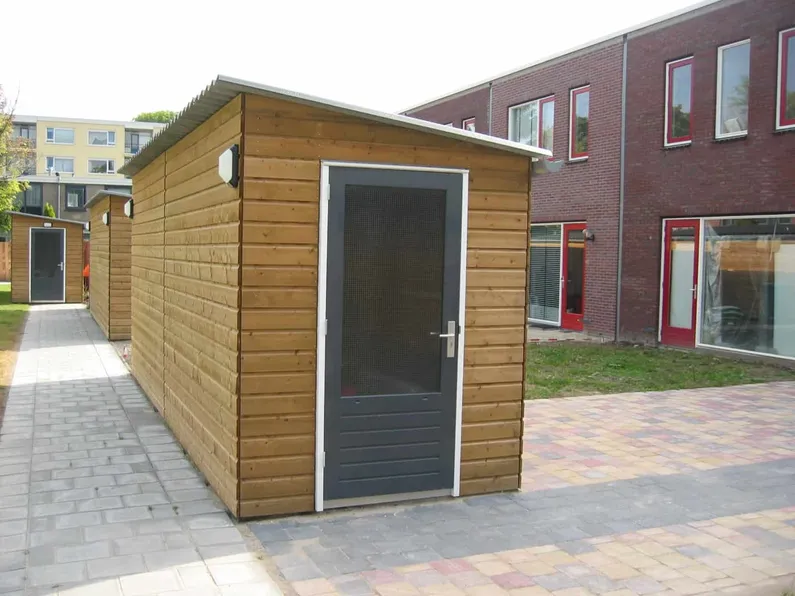 Berging met houtkleur met zwarte deur in achtertuin