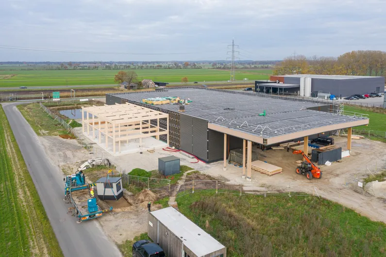 Een houten hal in aanbouw een groen landschap van bovenaf
