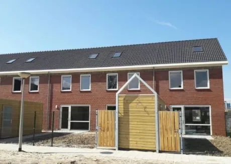 Nieuwbouwhuizen met rode stenen en zwart dak met gele schutting
