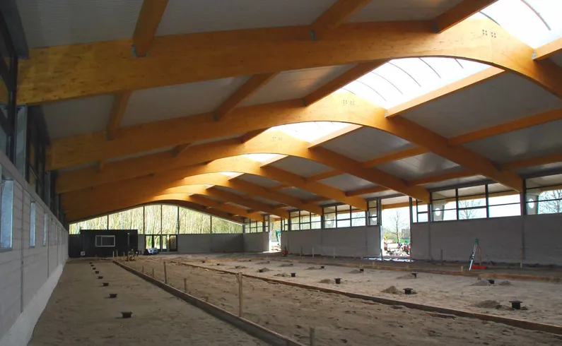Manege van houten balken en glas in het middelste gedeelte