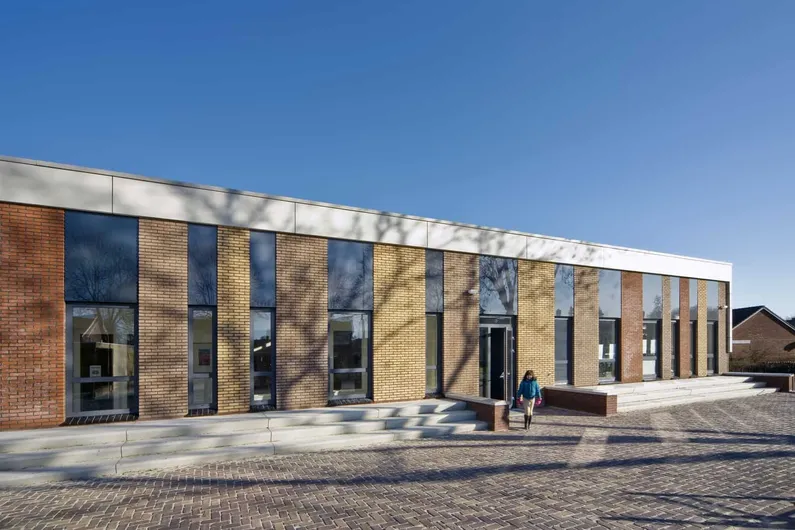 Gebouw met verschillende kleuren bakstenen en lange ramen met een trap ervoor