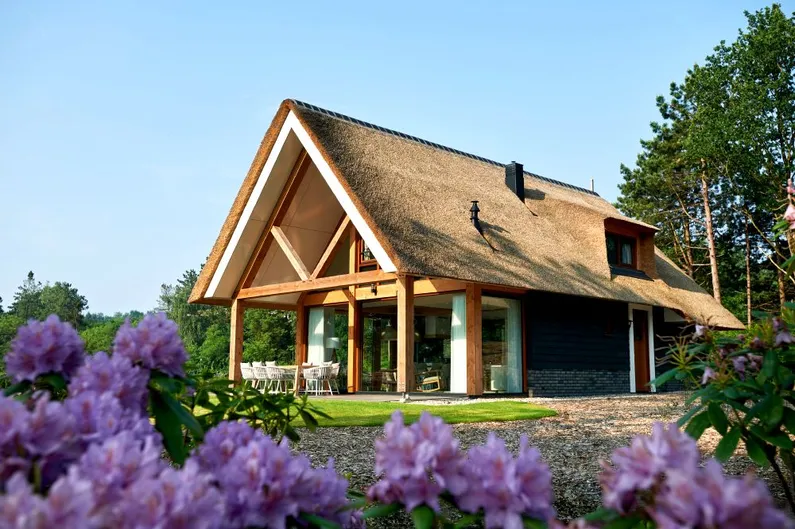 Vakantievilla met rieten dak en hout met paarse bloemen