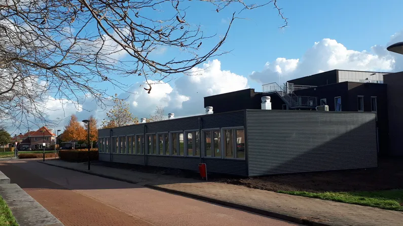 De lichtgrijze buitenkant van de tijdelijke school in Dronten