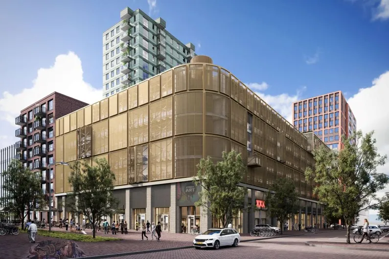 Hoge gebouwen met winkels, veel bomen en een gebouw met een ronde hoek met doorzichtig gele voorkant
