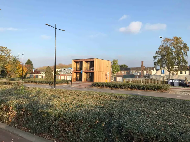 Houten en vierkante woning achter bosjes van veraf
