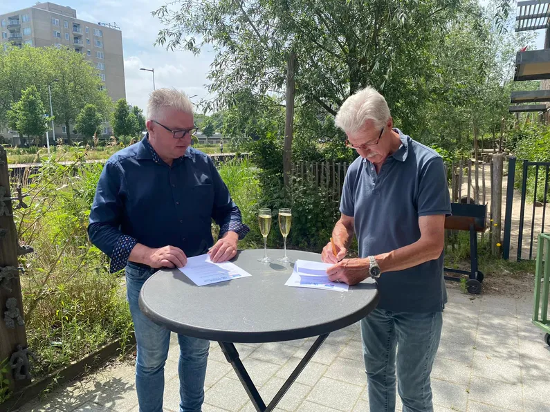 Twee mannen aan een ronde statafel een contract ondertekenen