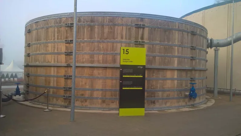 Een houten watertank op een terrein met een hal