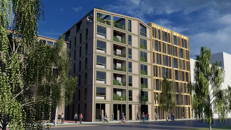 Houten appartementencomplex vanaf de straatkant met balkons met planten, bomen voor op de straat en lopende en fietsende mensen