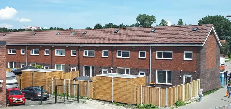 Rode rijtjeshuizen met gele strakke schuttingen die als afscheiding dienen van de tuin